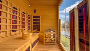 Eine Holzsauna mit Bücherregalen, einer hölzernen Sitzbank und Blick auf einen See.
