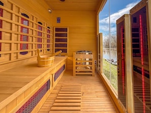 Eine Holzsauna mit Bücherregalen, einer hölzernen Sitzbank und Blick auf einen See.