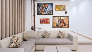 Ein Wohnzimmer mit einer Couch, passendem Hocker und einer Wand mit gerahmten Kunstwerken.