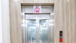 Ein Aufzug mit digitaler Anzeige, einem Schild für eine Personengruppe und einem grünen Kunstgrase-Boden.