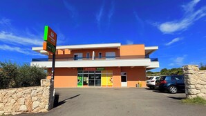 Un edificio de dos pisos con un letrero que dice 'STUDENAC MARKET' y un estacionamiento con coches.