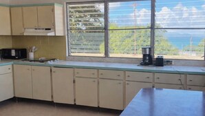 Una cocina con un ventanal grande, un ventilador de techo y armarios.