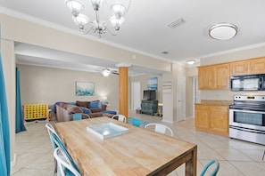 A spacious kitchen with wooden cabinets, a stainless steel oven, and a dining area with a wooden table and chairs. - Fire Pit | Walk to Beach in Minutes | Beach Gear (Gulf Shores)