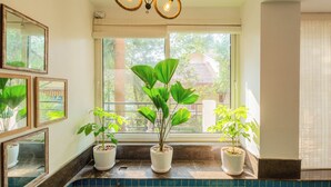 A bathroom with a window, potted plants, and a tiled backsplash. - Alaya Stays 3 BHK Casa Bella Vista  (Nerul)