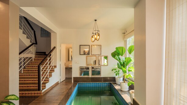 A home interior with a staircase, a tiled pool, and potted plants. - Alaya Stays 3 BHK Casa Bella Vista  (Nerul)