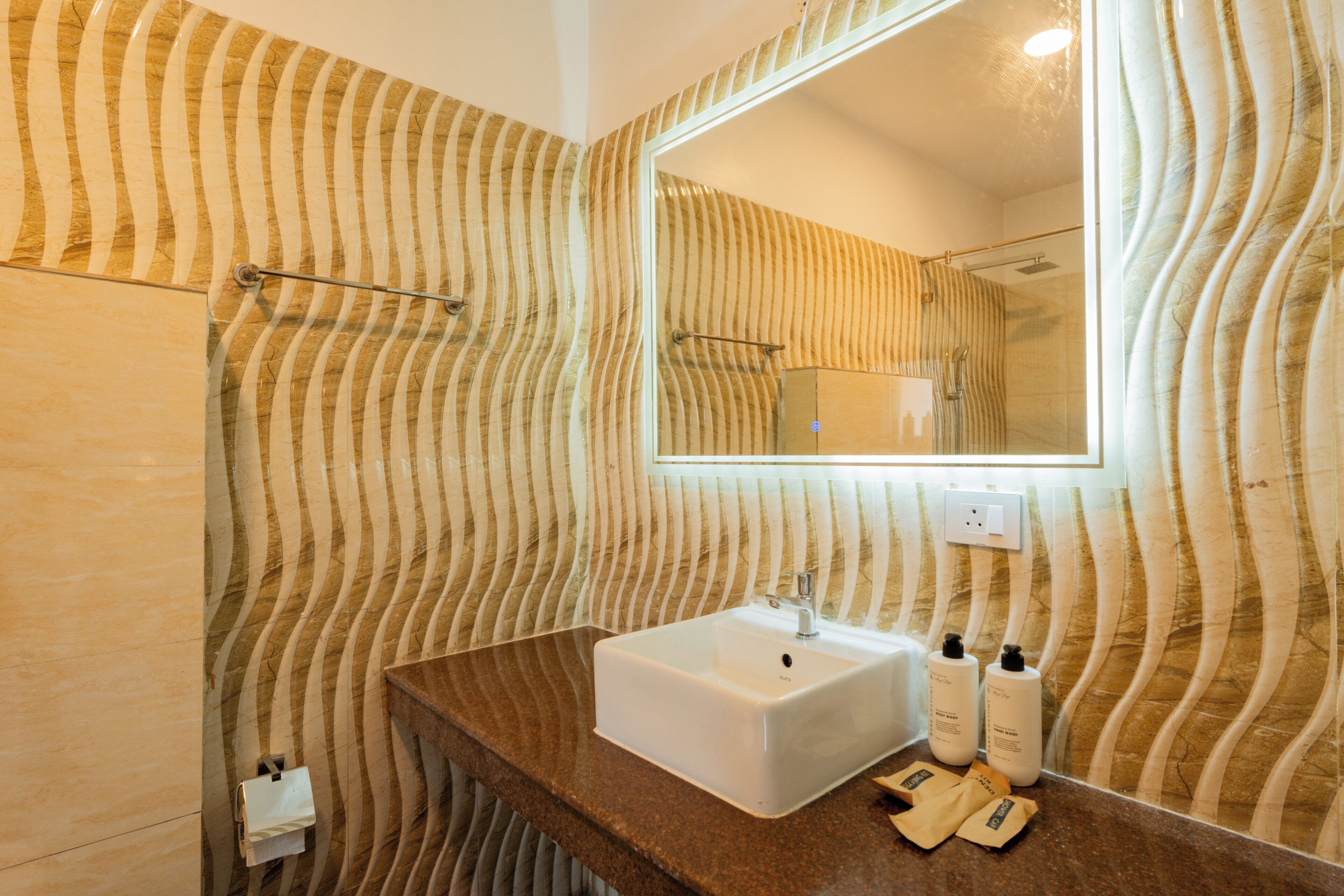 A bathroom with a patterned wall, a sink, a mirror, and a towel rack.