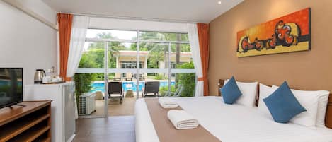 A hotel room with a large bed, a television, a desk with a chair, and a view of a pool and palm trees.