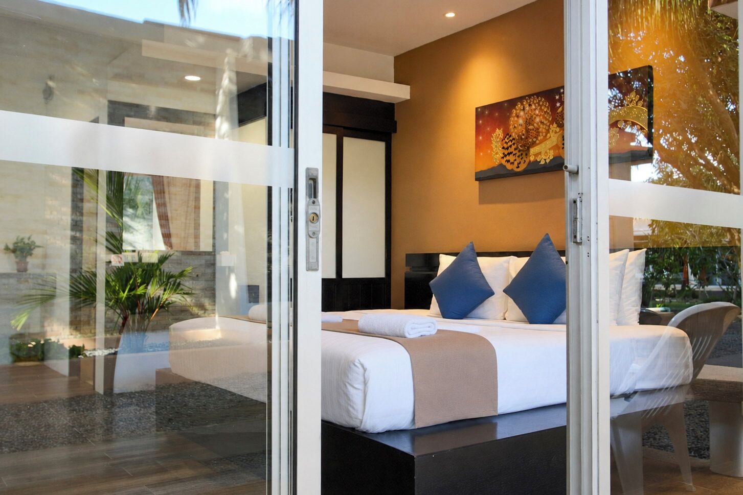Une chambre moderne avec un grand lit, une table de chevet et une porte vitrée donnant sur un balcon.
