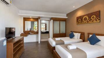 A hotel room with two beds, a TV, a desk, and a bathroom visible through an open door.