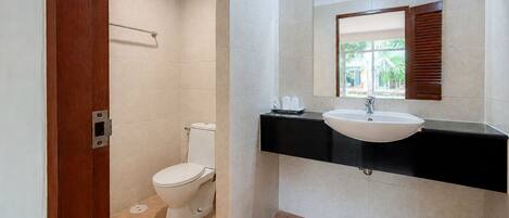 Un baño con inodoro, lavamanos y una ventana con persianas.