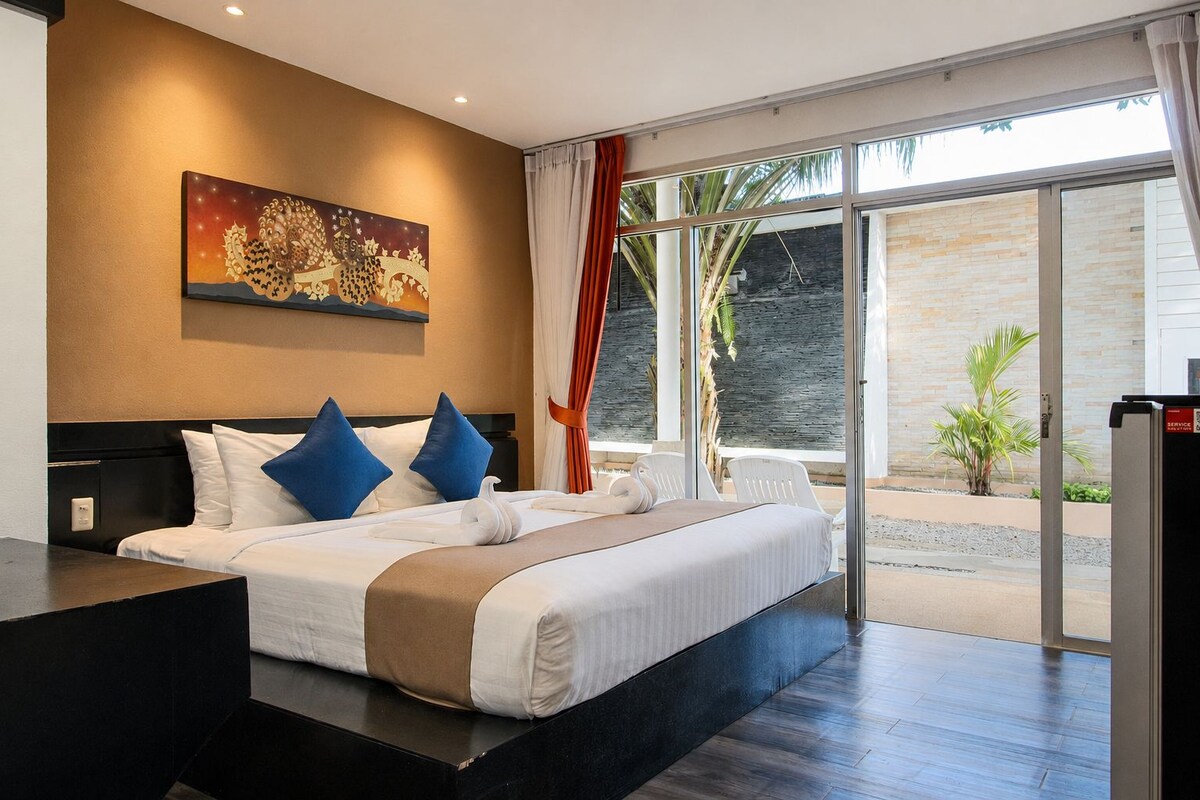Ein Hotelzimmer mit einem großen Bett, einem Gemälde an der Wand und Blick ins Freie.