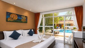 A hotel room with a bed, a painting, a view of a pool and outdoor seating, and a kitchenette. - Blue Palm Seafront Resort Phuket (Rawai)