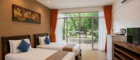 A hotel room with two beds, a television, a coffee maker, and a large window with curtains.