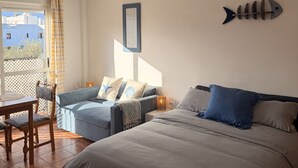 Ein Schlafzimmer mit einem Bett, einem Schlafsofa, einem Tisch und einem Sessel.