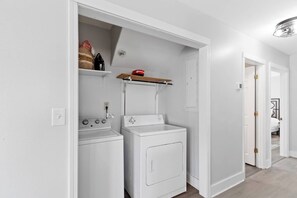 Une buanderie avec deux machines à laver blanches et une étagère au-dessus.