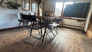 Een klaslokaal met houten vloer, een schoolbord en metalen stoelen.