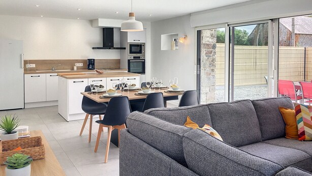Una cucina moderna con zona pranzo, un divano grigio e vista sull'esterno.