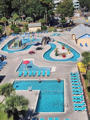 A swimming pool area with multiple pools, sun loungers, and a small bridge. - Perfect Paradise (Myrtle Beach)