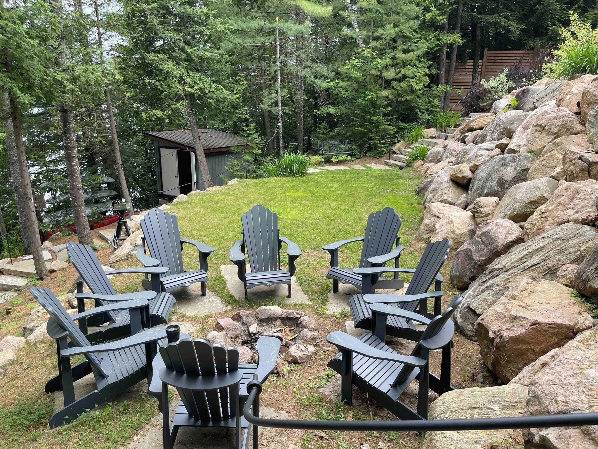 A backyard with Adirondack chairs, a small shed, and a rock garden.