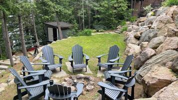 A backyard with Adirondack chairs, a small shed, and a rock garden.