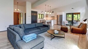A modern living room with a sectional sofa, a coffee table, and a leather armchair. - Serene 6-bedroom Retreat in Tory Hill With Lake Views (North Kawartha)