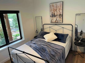 A bedroom with a bed, a window, a bedside table, a lamp, and a painting on the wall. - Serene 6-bedroom Retreat in Tory Hill With Lake Views (North Kawartha)