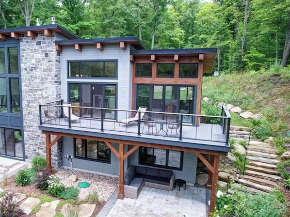 A modern two-story house with a balcony, stone facade, and large windows. - Serene 6-bedroom Retreat in Tory Hill With Lake Views (North Kawartha)