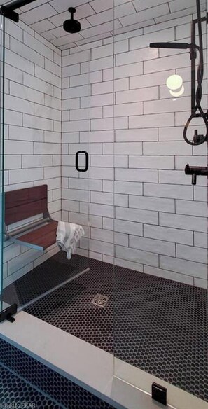 A shower with white tiled walls and a black floor. - Serene 6-bedroom Retreat in Tory Hill With Lake Views (North Kawartha)