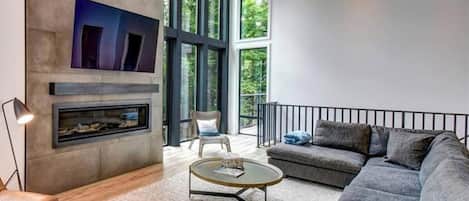 Una sala de estar moderna con chimenea, un sofá, una mesa de centro y un televisor.