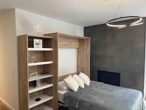 A bedroom with a bed, a built-in wardrobe, a wall-mounted decorative piece, and a modern light fixture. - Serene 6-bedroom Retreat in Tory Hill With Lake Views (North Kawartha)