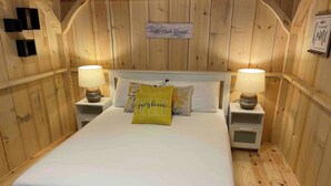 A wooden-paneled room with a bed, two bedside tables with lamps, and a sign on the wall. - Serene 6-bedroom Retreat in Tory Hill With Lake Views (North Kawartha)