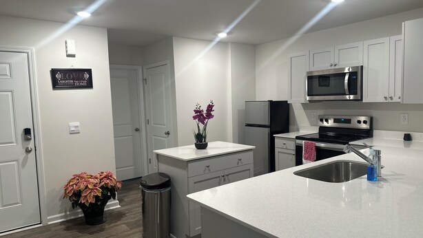 Una cocina moderna con armarios blancos, electrodomésticos de acero inoxidable y una isla central.