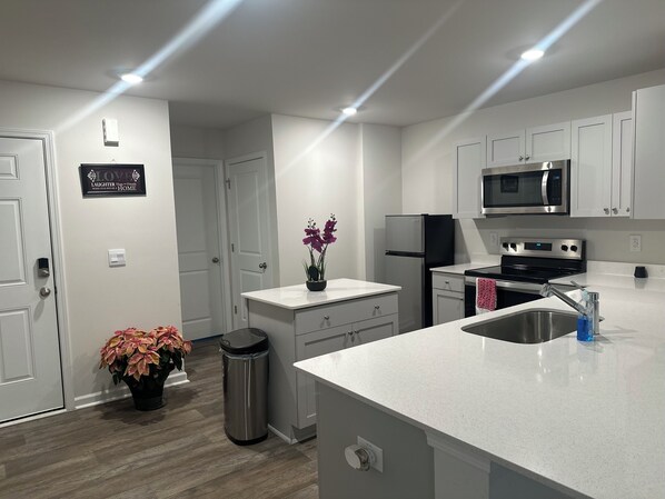 A modern kitchen with white cabinets, stainless steel appliances, and a central island.