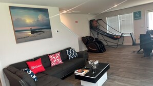 Una sala de estar con un sofá, una mesa de centro, un cuadro, una hamaca y un comedor.