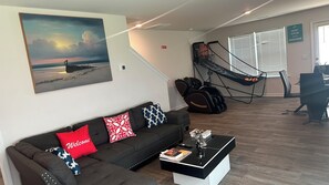 Una sala de estar con un sofá, una mesa de centro, un cuadro, una hamaca y un comedor.