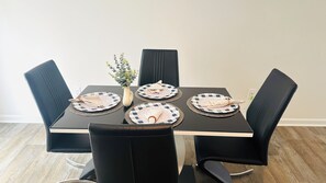 A dining table with four plates, a vase with a plant, and black chairs.