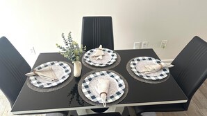 Una mesa de comedor con cuatro platos, un florero con follaje y una silla negra.