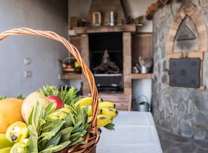 Ein Obst- und Gemüsekorb auf einem Tisch, im Hintergrund eine Steinswand und ein Kamin.