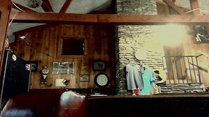 Ein rustikales Interieur mit Holzwänden, einer Steinwand, einer Holzbalkendecke und einer kleinen Wendeltreppe.