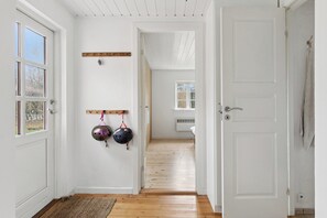 Un couloir doté d’un plancher en bois, de murs blancs et d’une porte donnant sur une autre pièce.