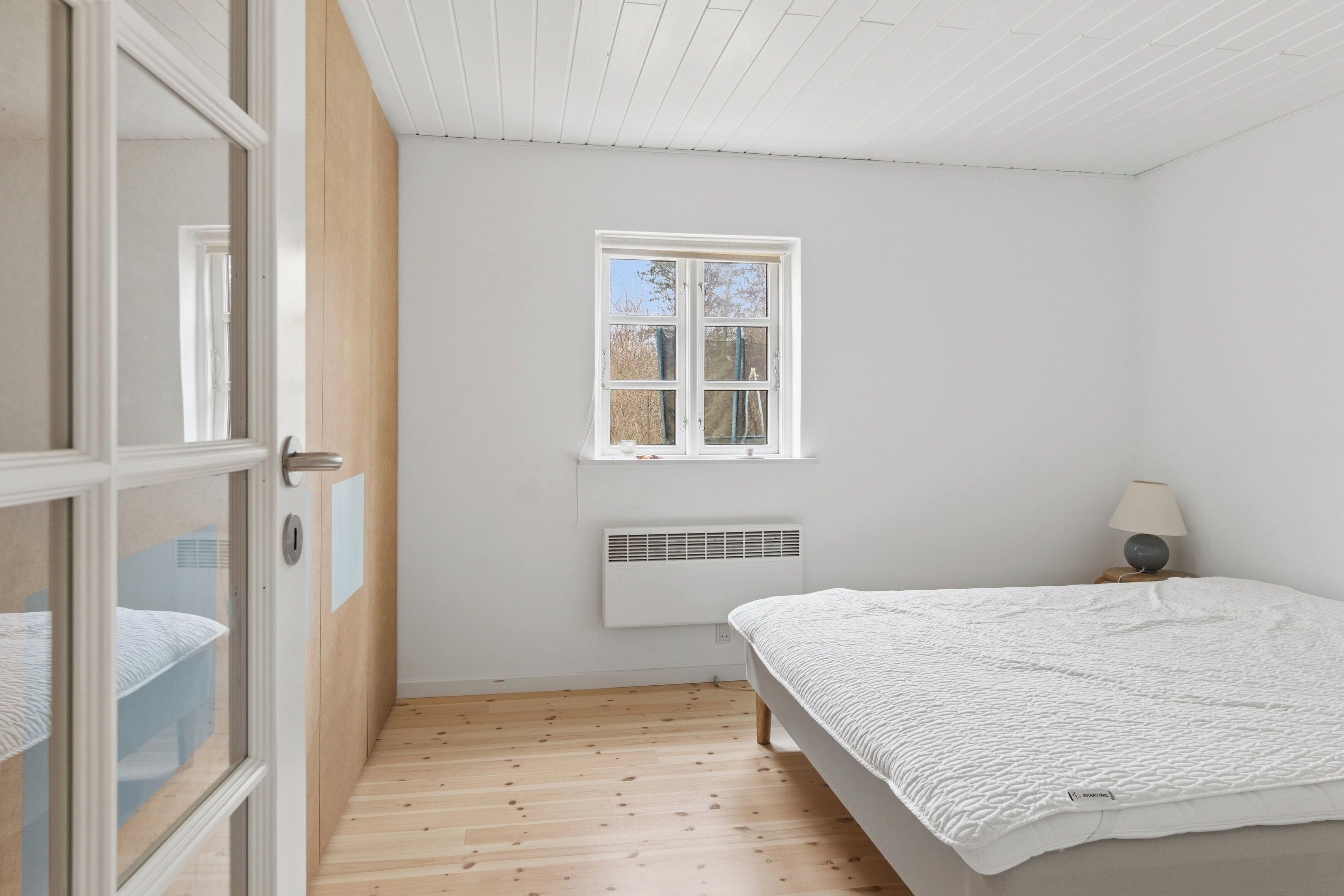 Une chambre à coucher avec un lit, une fenêtre, un radiateur et une porte.