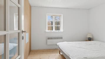 Une chambre à coucher avec un lit, une fenêtre, un radiateur et une porte.