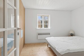 Ein Schlafzimmer mit Bett, Fenster, Heizung und Tür.