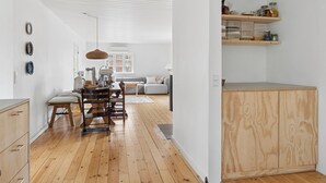 Eine moderne Küche mit Holzboden, einer Essecke mit Tisch und Stühlen sowie einem eingebauten Holzschrank.