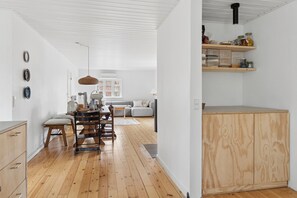 Eine moderne Küche mit Holzboden, einer Essecke mit Tisch und Stühlen sowie einem eingebauten Holzschrank.