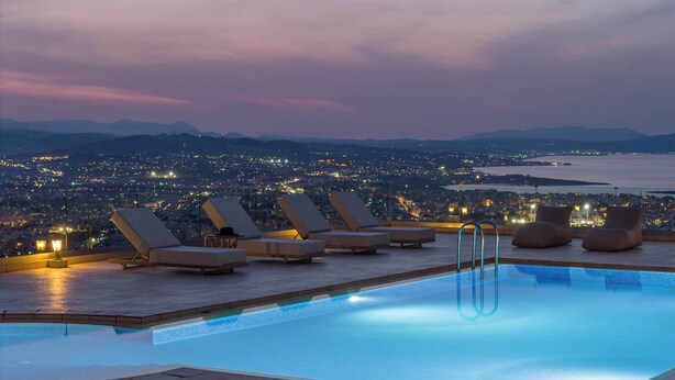A rooftop pool with lounge chairs and a cityscape view at dusk. - Lithea Seaview Villa & Estate (Chania)