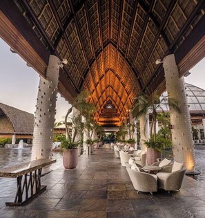 A covered outdoor area with a thatched roof, stone pillars, and lounge furniture. - PGA Mexico Open @ Vidanta 
Grand Luxxe One Bedroom Presidential Villa (Bahía de Banderas)
