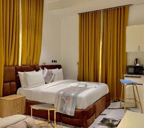 A hotel room with a bed, bedside table, lamp, and a desk with a chair.