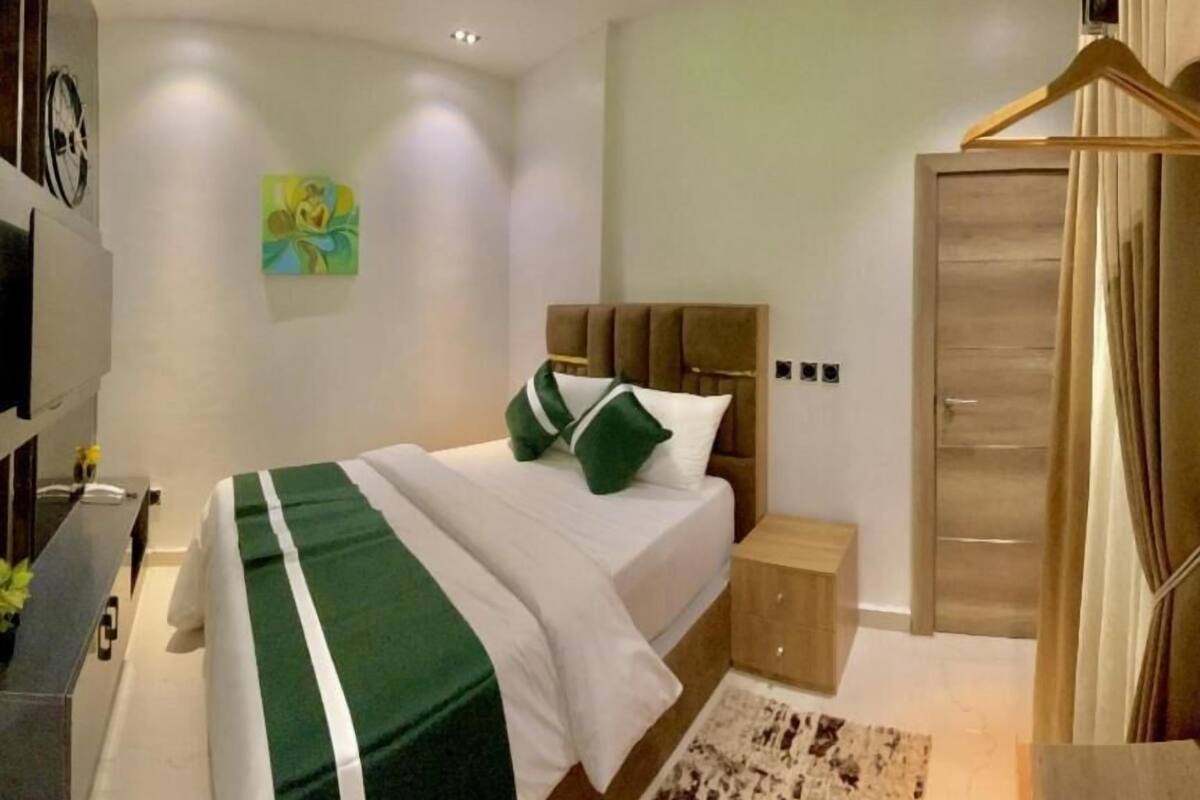 Un dormitorio moderno con una cama, mesitas de noche, un armario y un televisor montado en la pared.