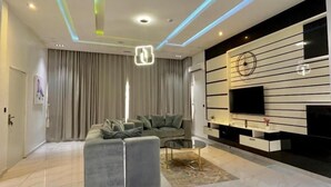 Una sala moderna con un sofá seccional, una mesa de centro, un televisor de pantalla plana y un mueble de entretenimiento fijado a la pared.